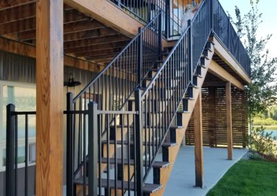 An exterior wooden staircase with black handrails